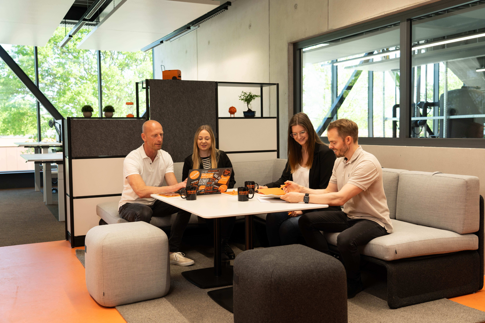 Employees and young professionals at KEMPER working together on projects in a modern work environment