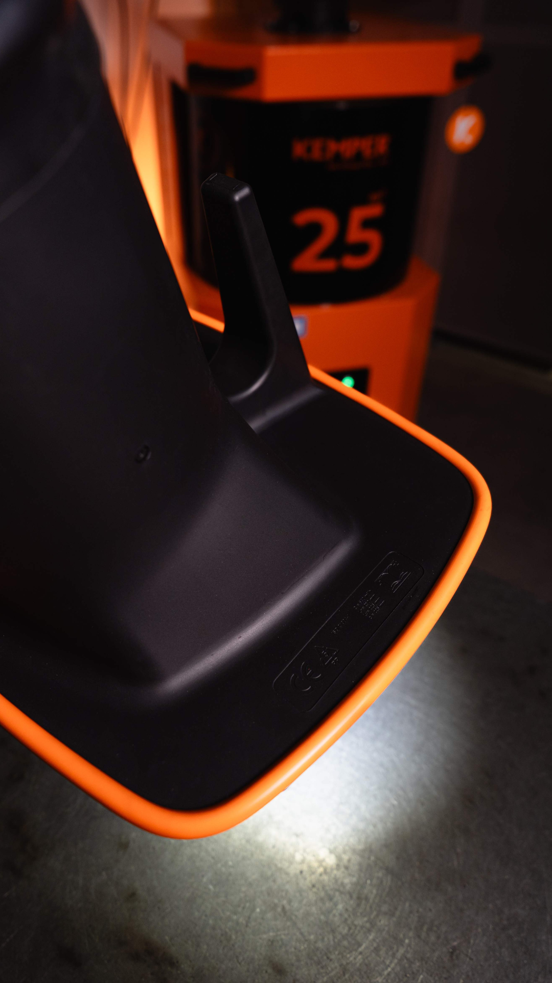 Close-up of an extraction hood with illuminated edge in front of an extraction unit in an industrial environment.