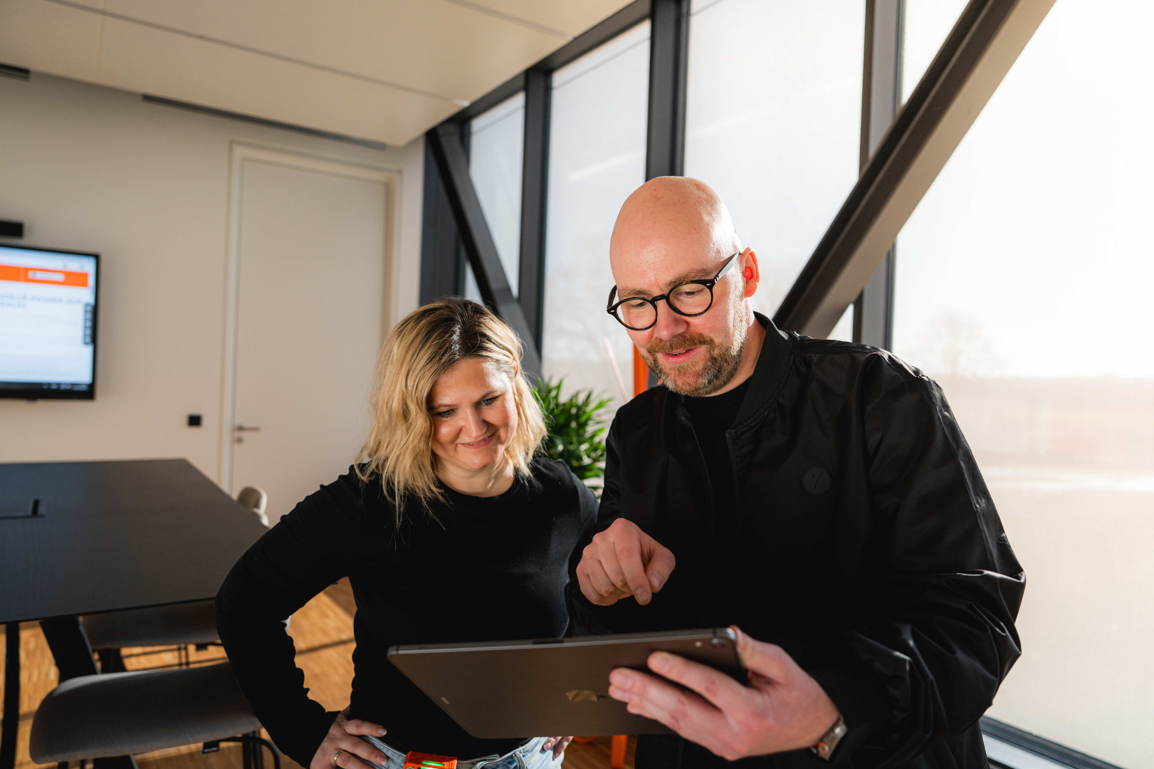 Two employees at KEMPER collaborating on a tablet in a modern office