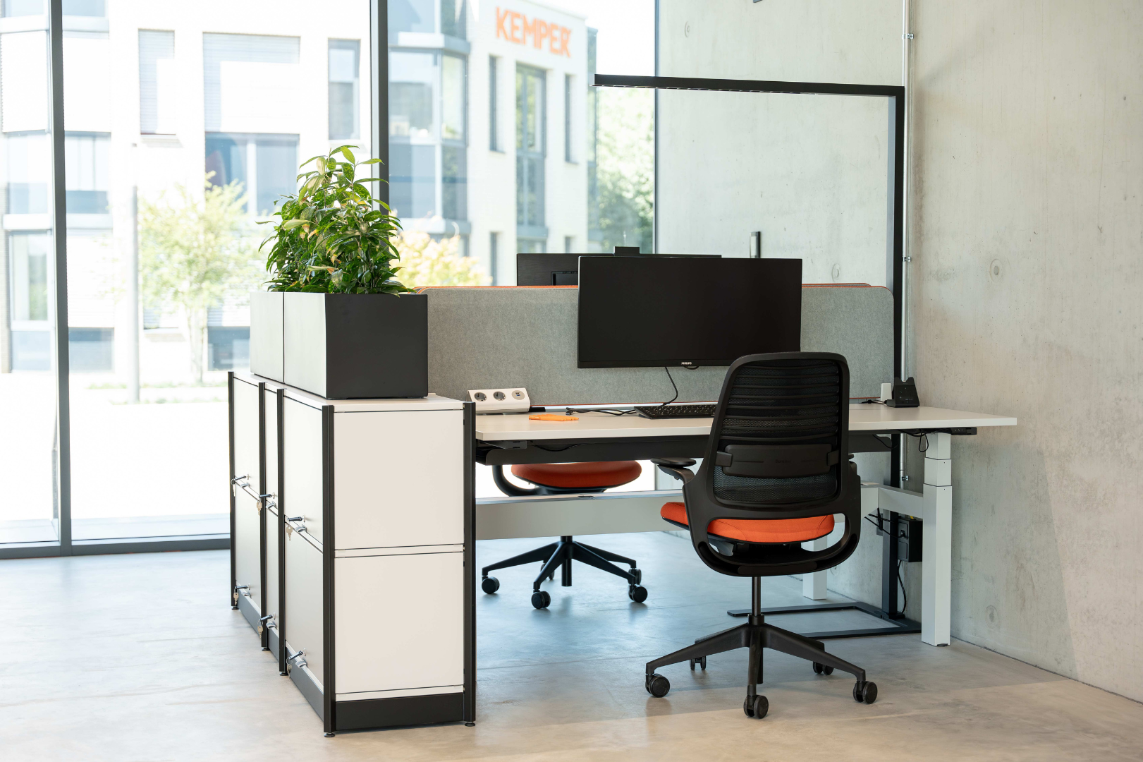 Modern office workspace with desk, monitor, office chair and plant at KEMPER headquarters