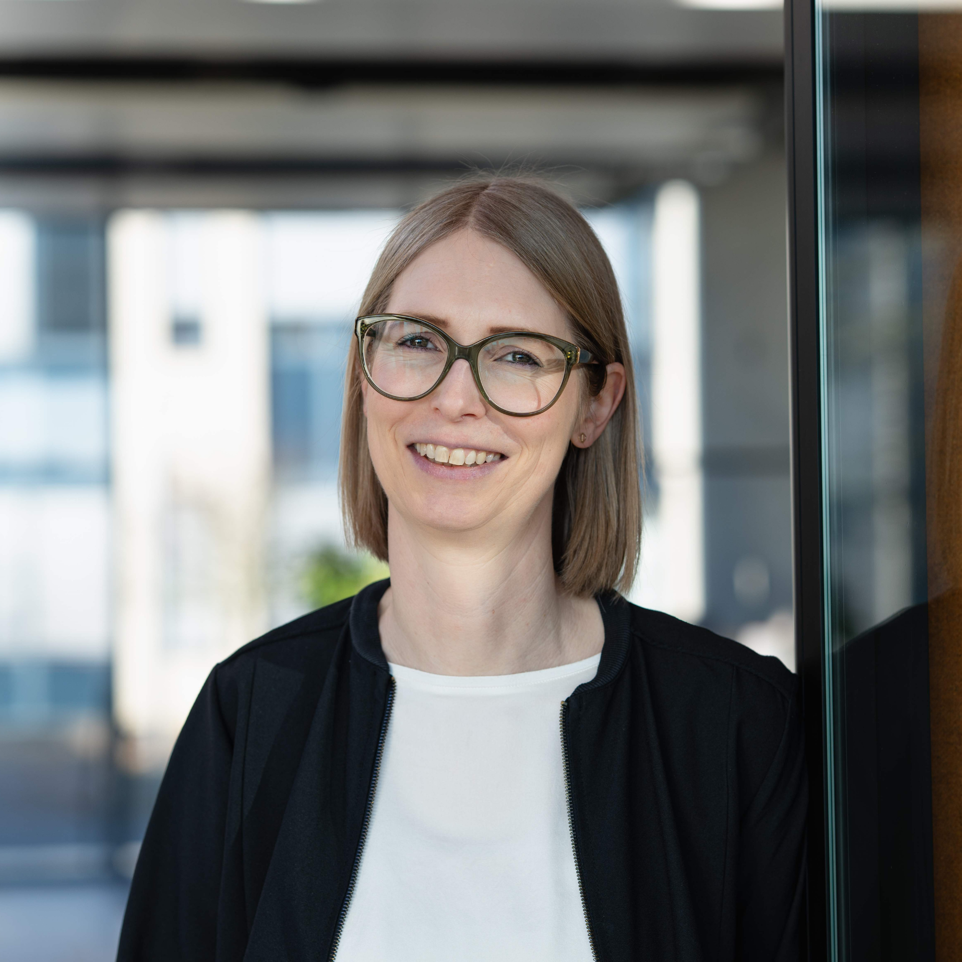 Portrait of a smiling employee with glasses in a modern office environment